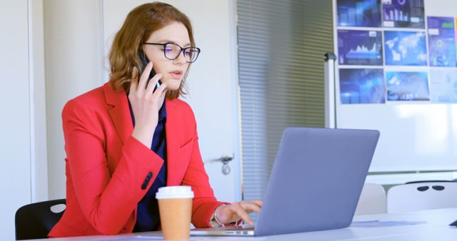 Businesswoman in Red Blazer Working on Laptop and Talking on Phone in Office - Download Free Stock Images Pikwizard.com