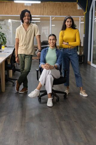 Diverse team posing confidently in modern open-plan office, seated leader in chair