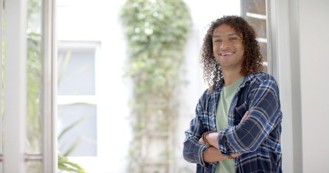 Casual Young Man with Curly Hair Smiling and Crossing Arms Indoors - Download Free Stock Images Pikwizard.com