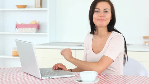 Smiling Woman Typing on Laptop in Kitchen Setting