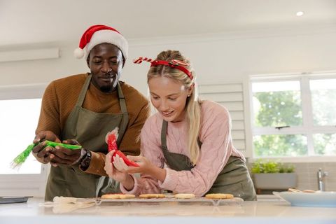Festive Couple Joyfully Decorating Holiday Cookies in Kitchen