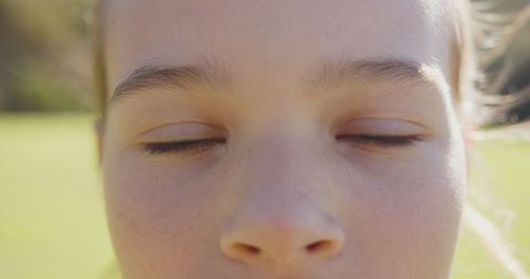 Close-up of girl's eyes closed with sunny background