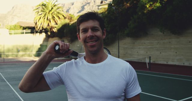 Happy man standing on tennis court holding racket - Download Free Stock Images Pikwizard.com