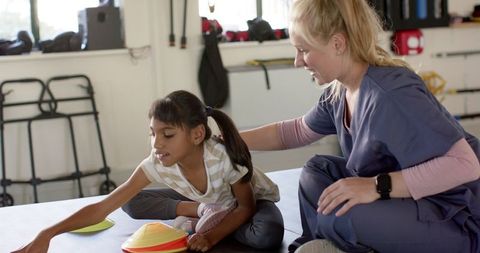 Young Girl in Physiotherapy Playing with Therapy Cones Guided by Therapist