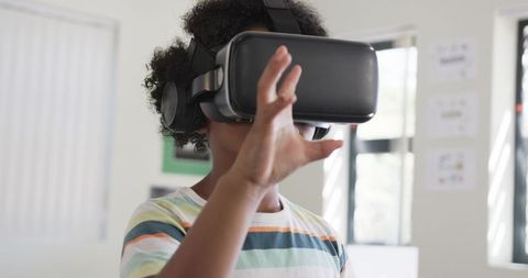 African American Teen Exploring Virtual Reality Classroom with Headset and Headphones