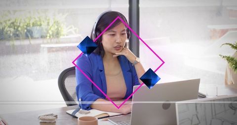 Professional woman wearing headset and blue blazer participating in virtual meeting on laptop