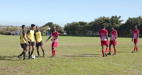 Amateur soccer practice with diverse male teams on green field