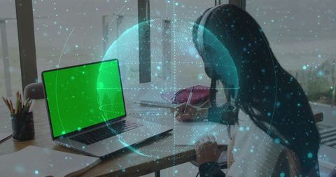 Teen studying at home desk with green-screen laptop and holographic AR globe overlay