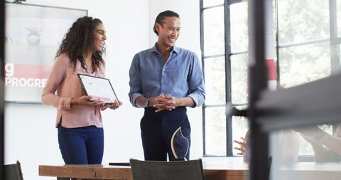 Colleagues celebrating employee achievement in office meeting