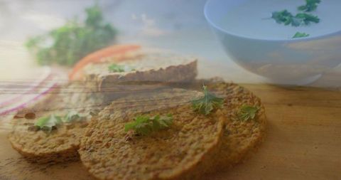 Herbed lentil patties sitting on wooden board with parsley garnish and creamy dip