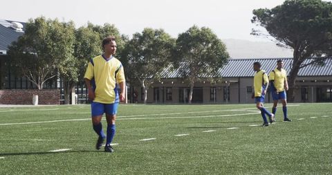 Diverse male soccer players warming up on grassy field