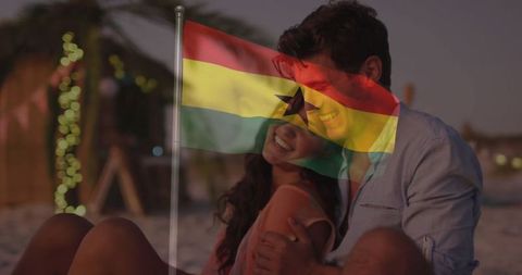 Couple hugging at twilight with ghana flag overlay on beach