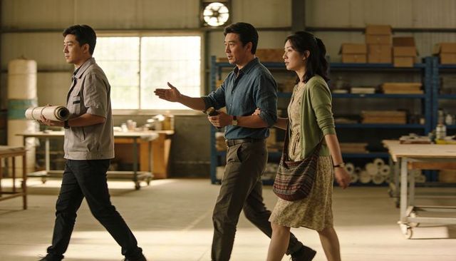 Walking coworkers discussing blueprints in industrial workshop during daylight planning