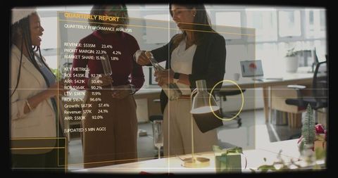 Pouring drinks and reviewing quarterly report overlay during casual office celebration