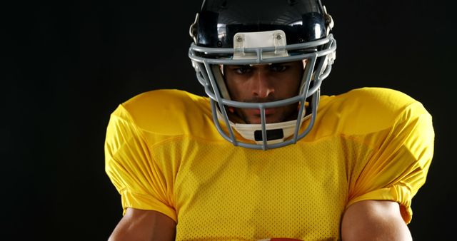 American football player in uniform looking determined against dark background - Download Free Stock Images Pikwizard.com