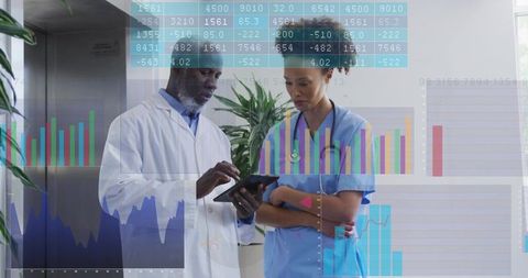 Physician and nurse reviewing tablet with data and charts overlay in hospital corridor