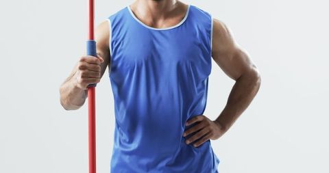 Young male athlete holding javelin in studio competition pose