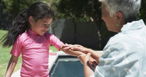 Applying sunscreen to child at backyard pool, summer sun protection and caregiving