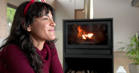 Woman relaxing by cozy fireplace in festive headband
