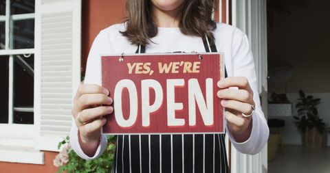 Waitress holding open sign at cafe entrance