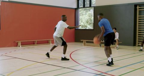 African american men dribbling basketball crossover on indoor court practicing athletic skill