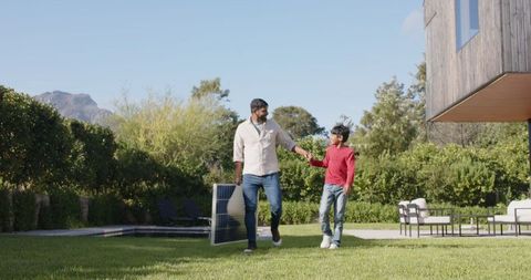 Father and Son Carrying Solar Panel in Sunny Backyard