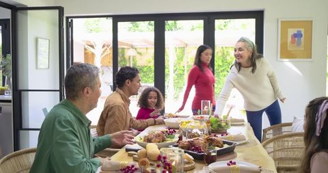 Multigenerational diverse family gathering around festive dining table sharing roast turkey