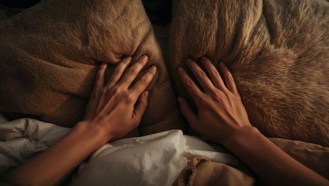Hands pressing soft brown pillows on white duvet, cozy bedroom flatlay