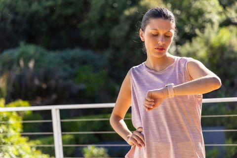 African american woman checking smartwatch on balcony during outdoor fitness routine