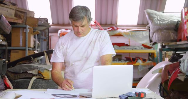 Middle-aged Man Working on Blueprint in Auto Workshop - Download Free Stock Images Pikwizard.com