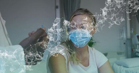 Doctor giving vaccine to masked patient receiving injection in clinic with network overlay