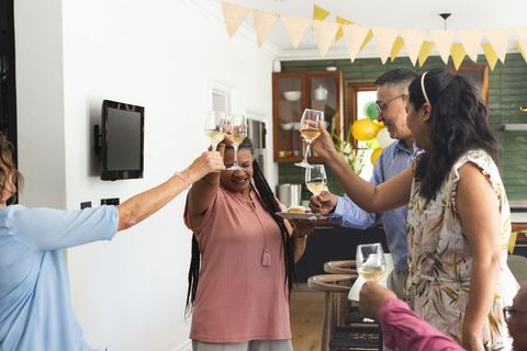 Multigenerational family toasting with wine and appetizers in bright home kitchen