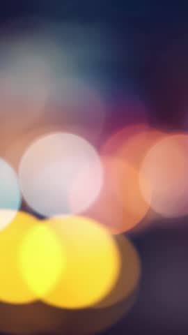 Vertical abstract bokeh lights shifting from white to orange on dark background