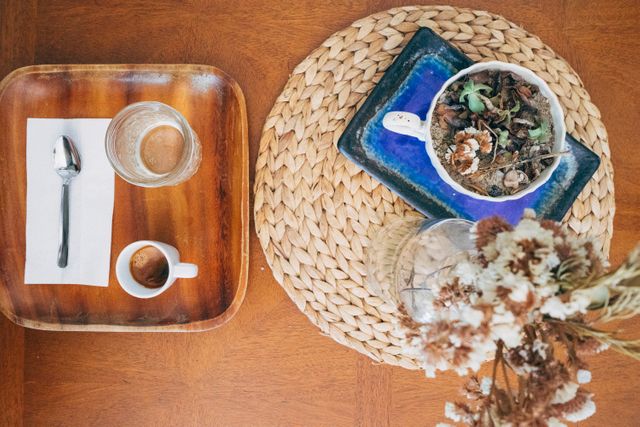 Overhead view shows empty coffee cup, dried tea leaves, and decorative elements on wooden table. Great for illustrating homey, cafe, or rustic themes. Useful for blogs, social media, and websites focusing on coffee, relaxation, or interior design.