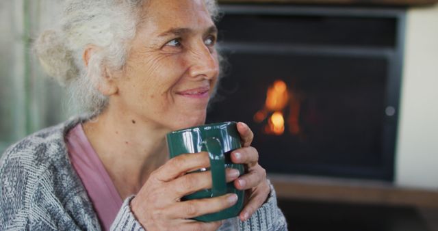 Senior Woman Enjoying Hot Drink by Fireplace on Winter Evening - Download Free Stock Images Pikwizard.com