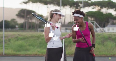 Joyful tennis female players relaxing on court after game