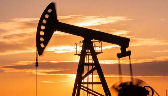 Sunset silhouette pumpjack with walking beam and horsehead on rural oilfield