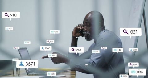 Senior manager making business call while pointing at laptop with notification overlays