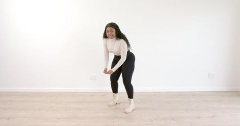 Woman tying shoelaces in bright living room preparing for workout