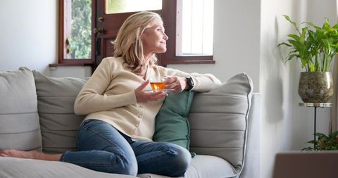 Senior Woman Relaxing with Tea on Sofa in Cozy Living Room
