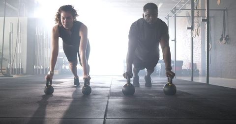 Focused Workout Partners Exercising with Kettlebells in Gym