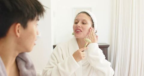 Couple enjoying morning skincare routine with jade roller in bright bathroom