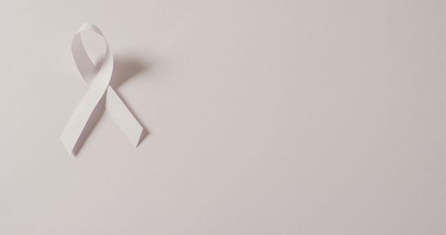 Image of white lung cancer ribbon on pale blue background. medical and healthcare awareness support campaign symbol for lung cancer.