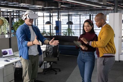 Multigenerational team testing vr headset in modern open-plan office for collaboration