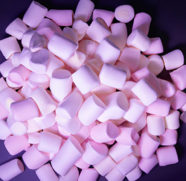 Close-up showing a pile of pastel pink and white marshmallows against a dark background. Useful for websites, blogs, or advertisements focused on sweets, desserts, or party planning. Ideal for illustrating candy shop products, festive treats, or snack ideas.