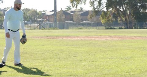 Sunlit baseball outfielder standing on grassy field holding glove watching play ready for defense