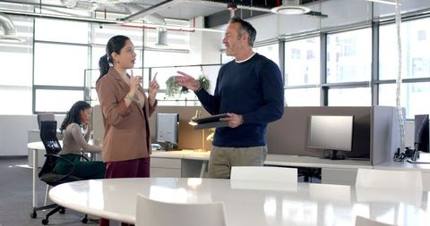 Diverse team collaborating in modern open-plan office around round white meeting table