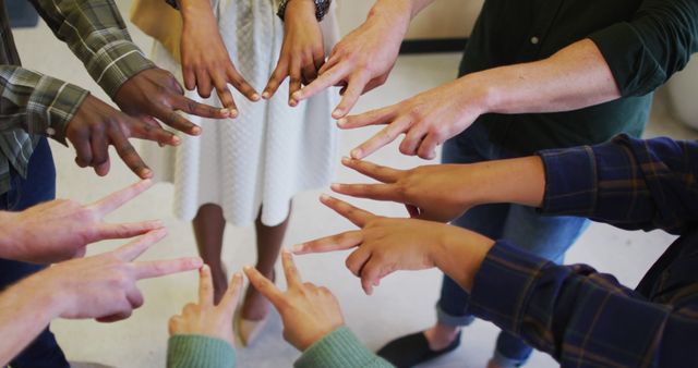 Multiracial group of individuals forming unity gesture with hands, symbolizing collaboration and teamwork. Great for concepts related to diversity, inclusion, teamwork, partnerships, and community initiatives.