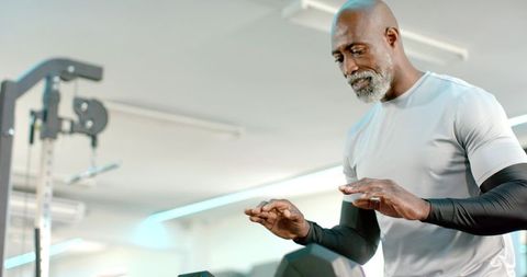 Senior african american man adjusting cardio console while training in modern gym