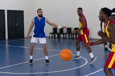 Diverse basketball players engaged in intense game on indoor court